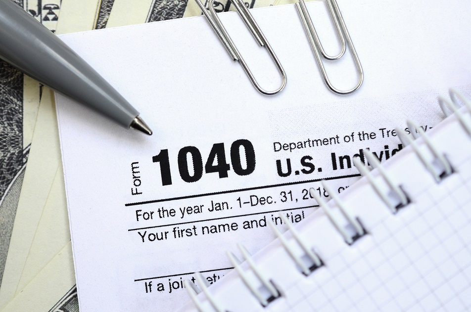 The pen, notebook and dollar bills is lies on the tax form 1040 U.S. Individual Income Tax Return. The time to pay taxes